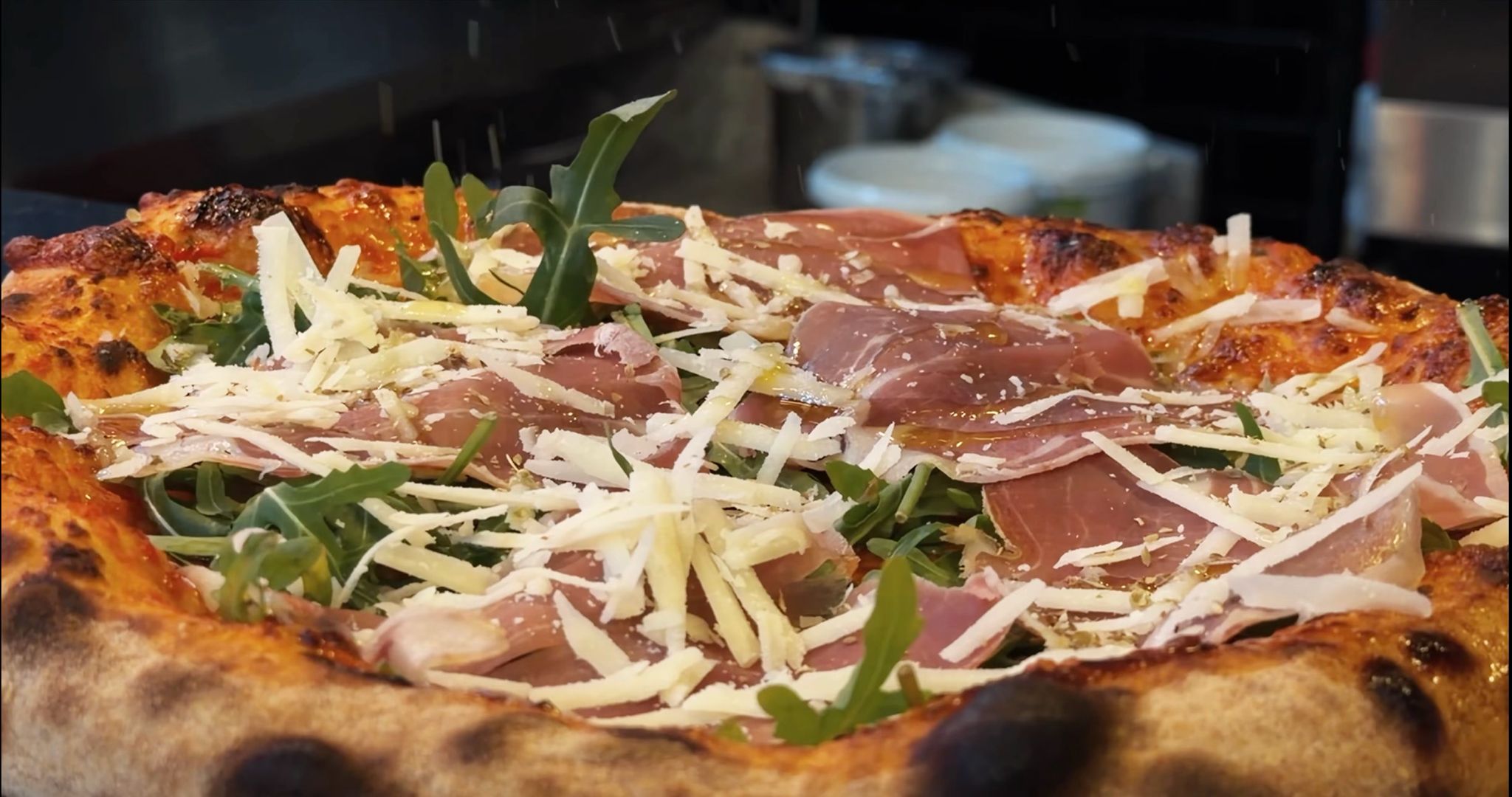 Pizza mit Rucola, Schinken und Käse
